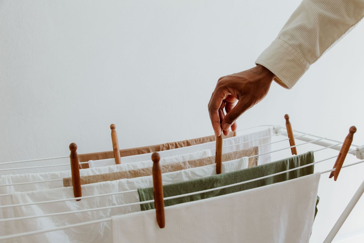 A hand placing a garment on an indoor drying rack