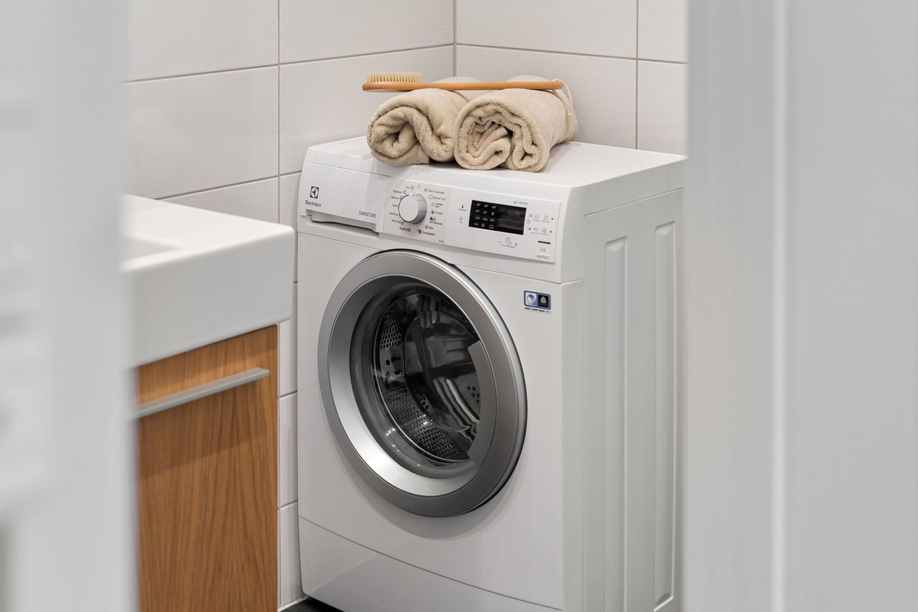 A bright laundry room with a white washing machine and folded towels on top