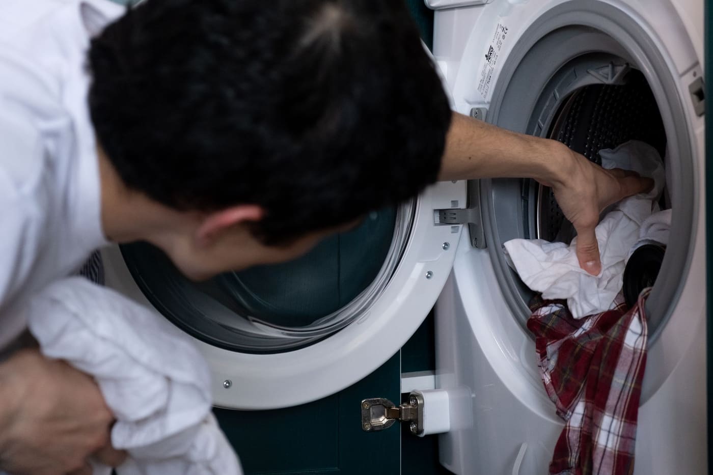 A man placing clothes into a washing machine