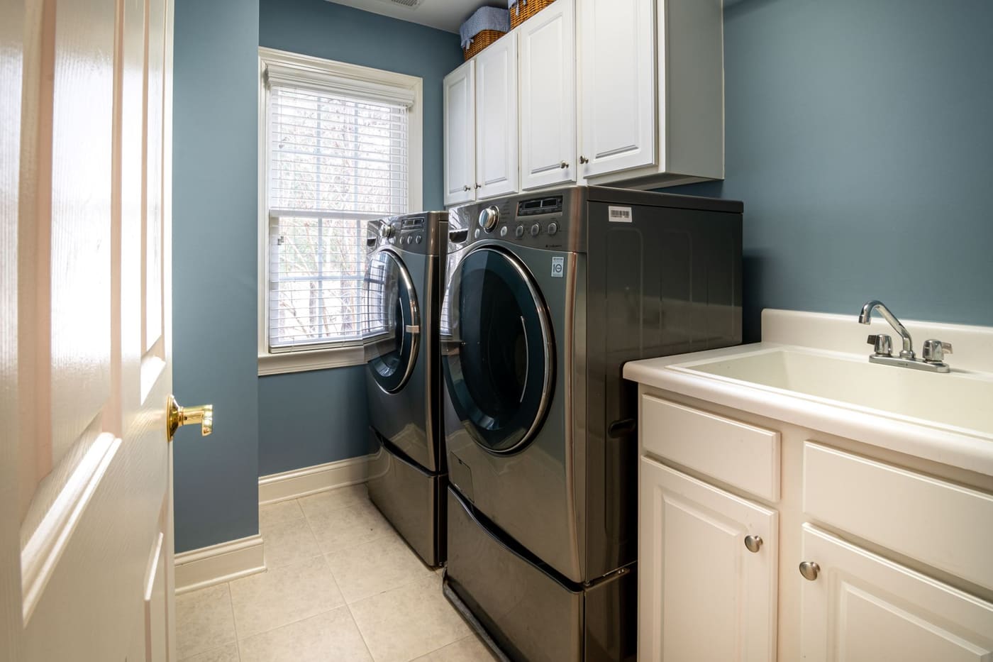 A tidy home laundry room with a washer and dryer side by side and a utility sink
