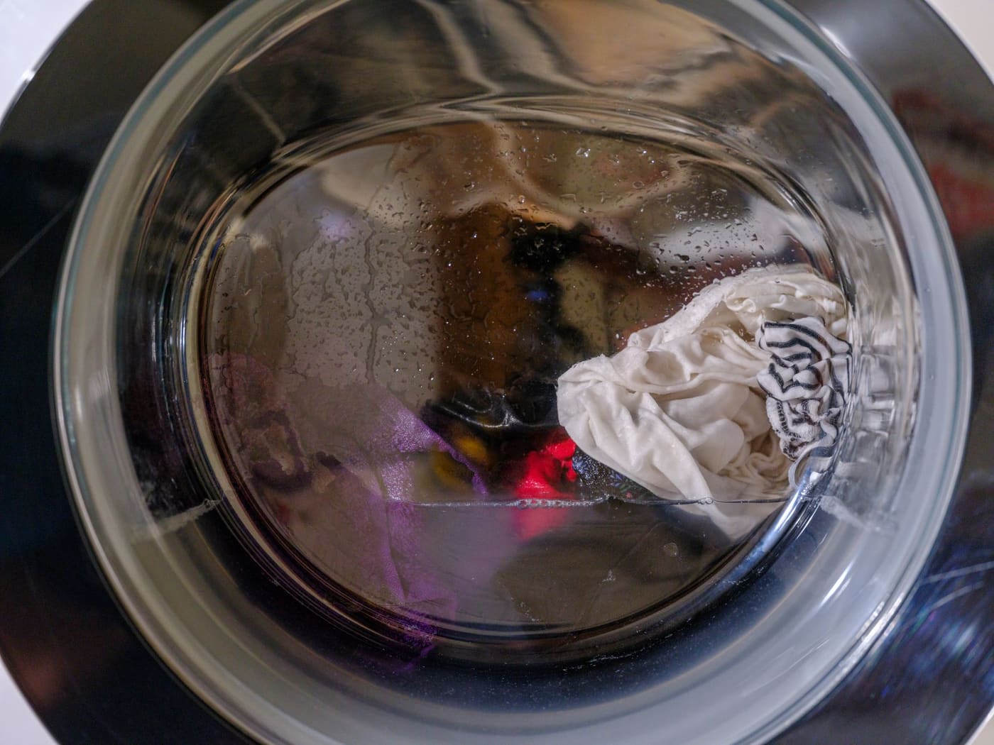 Wet clothes moving inside the glass door of a front-loading washing machine